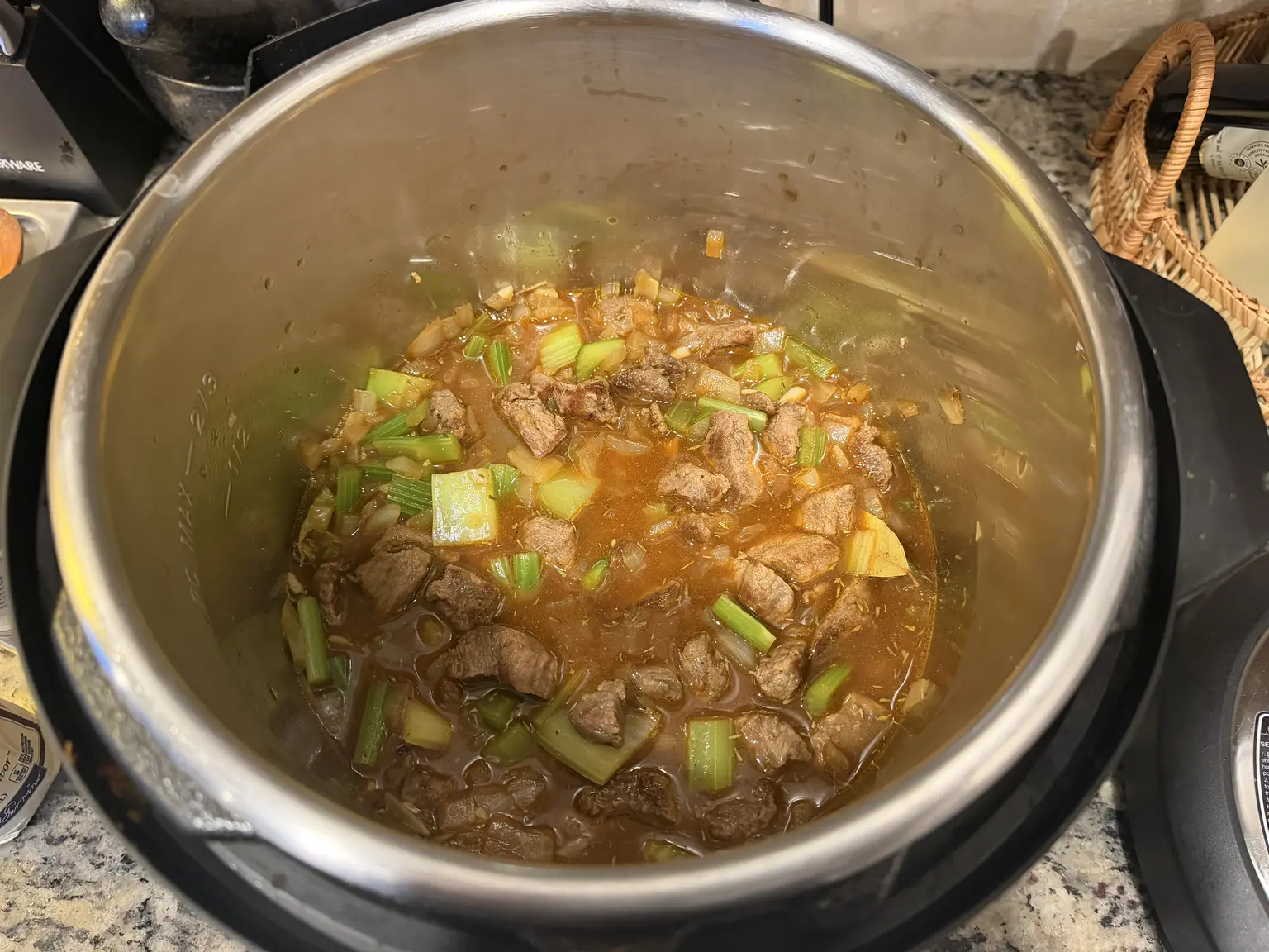 Seared beef, vegetables, broth, and a bay leaf in the Instant Pot before pressure cooking.